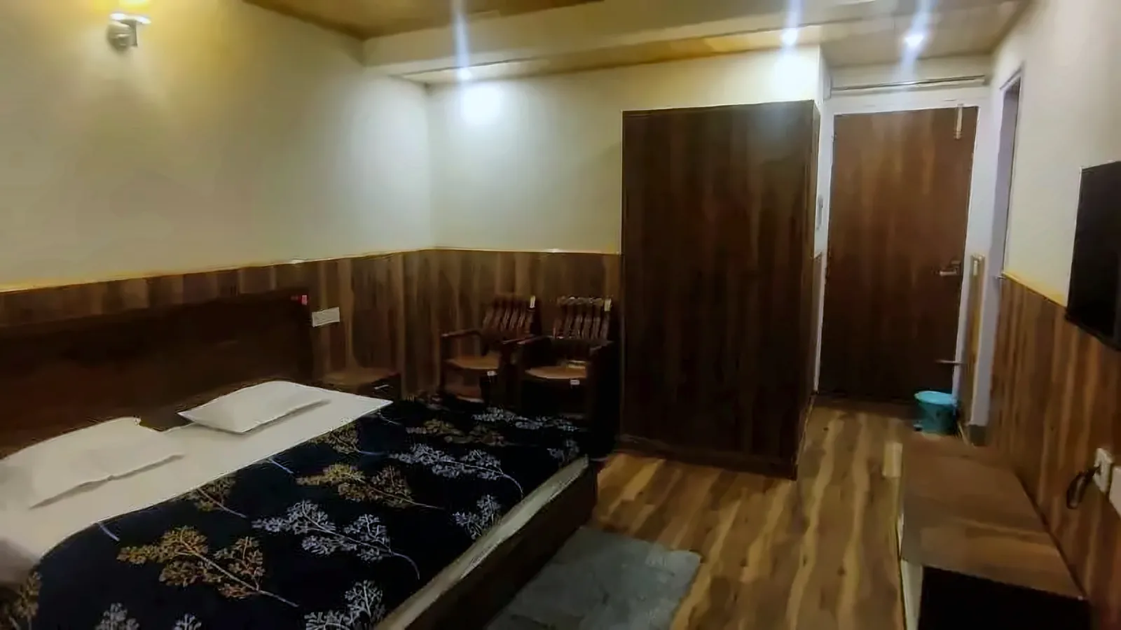 Spacious room at Gayatri Lodge with a double bed, seating corner and wardrobe