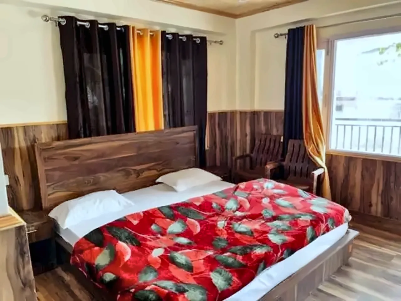 Room at Gayatri Lodge with a window, wooden bed and seating